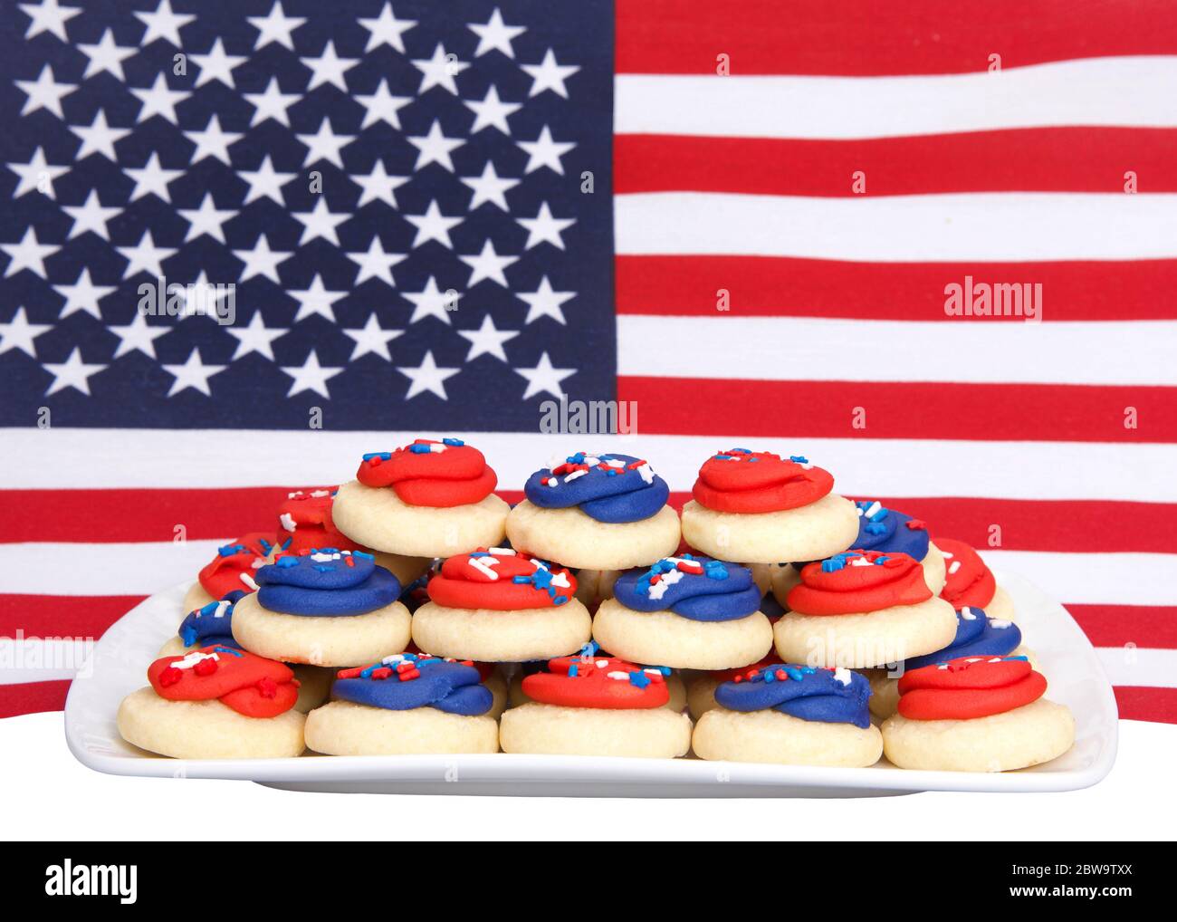 Nahaufnahme auf rechteckigen Porzellanteller aus Milchzucker-Cookies wtih Süßigkeiten Streuseln vor einem aus der Fokus American Flag. Patriotische Cookies. Stockfoto