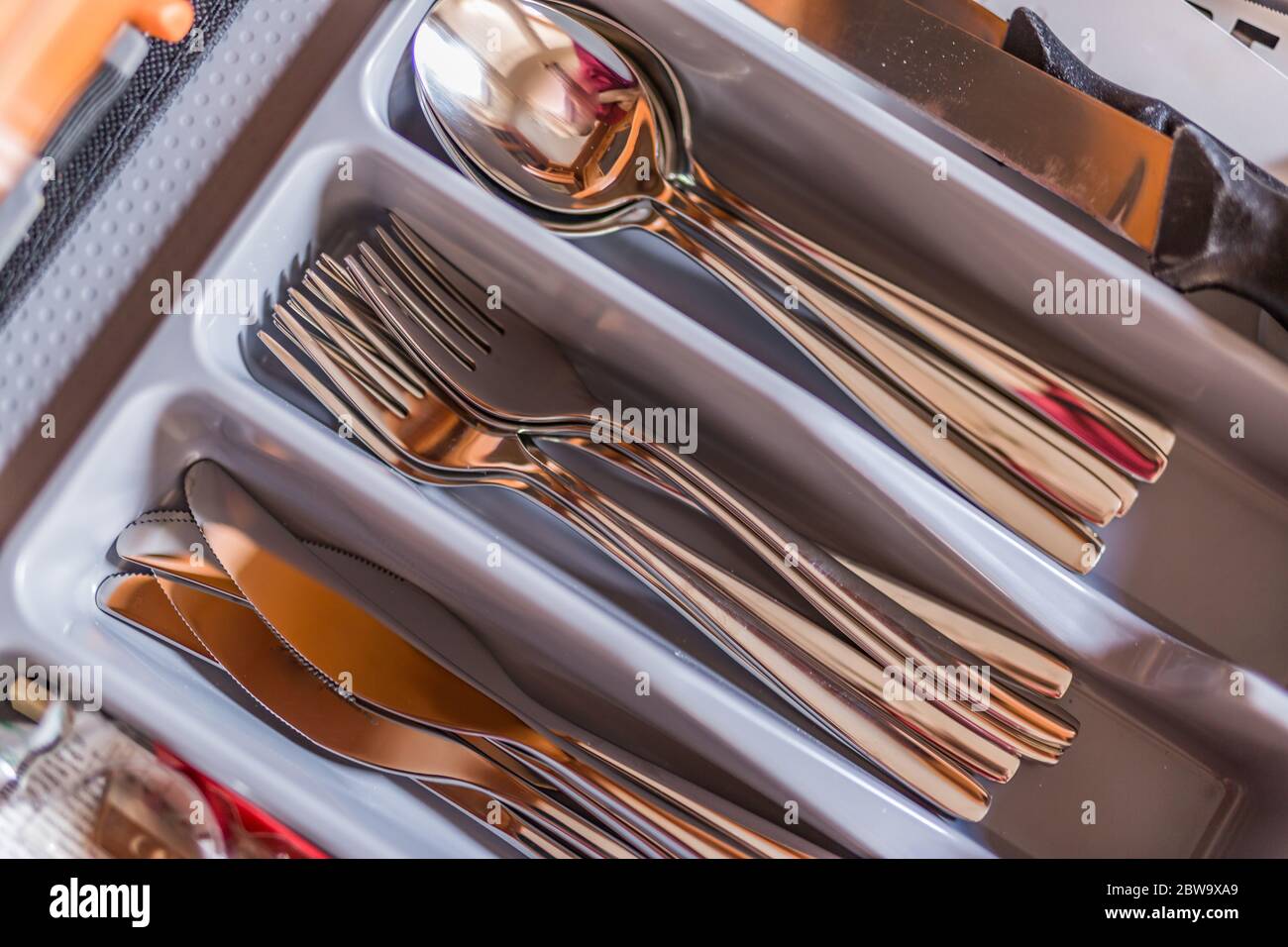 Offene Küchenschublade mit Tablett und Besteck im Inneren. Graue Vorderseite der Schublade, innen weiß Stockfoto