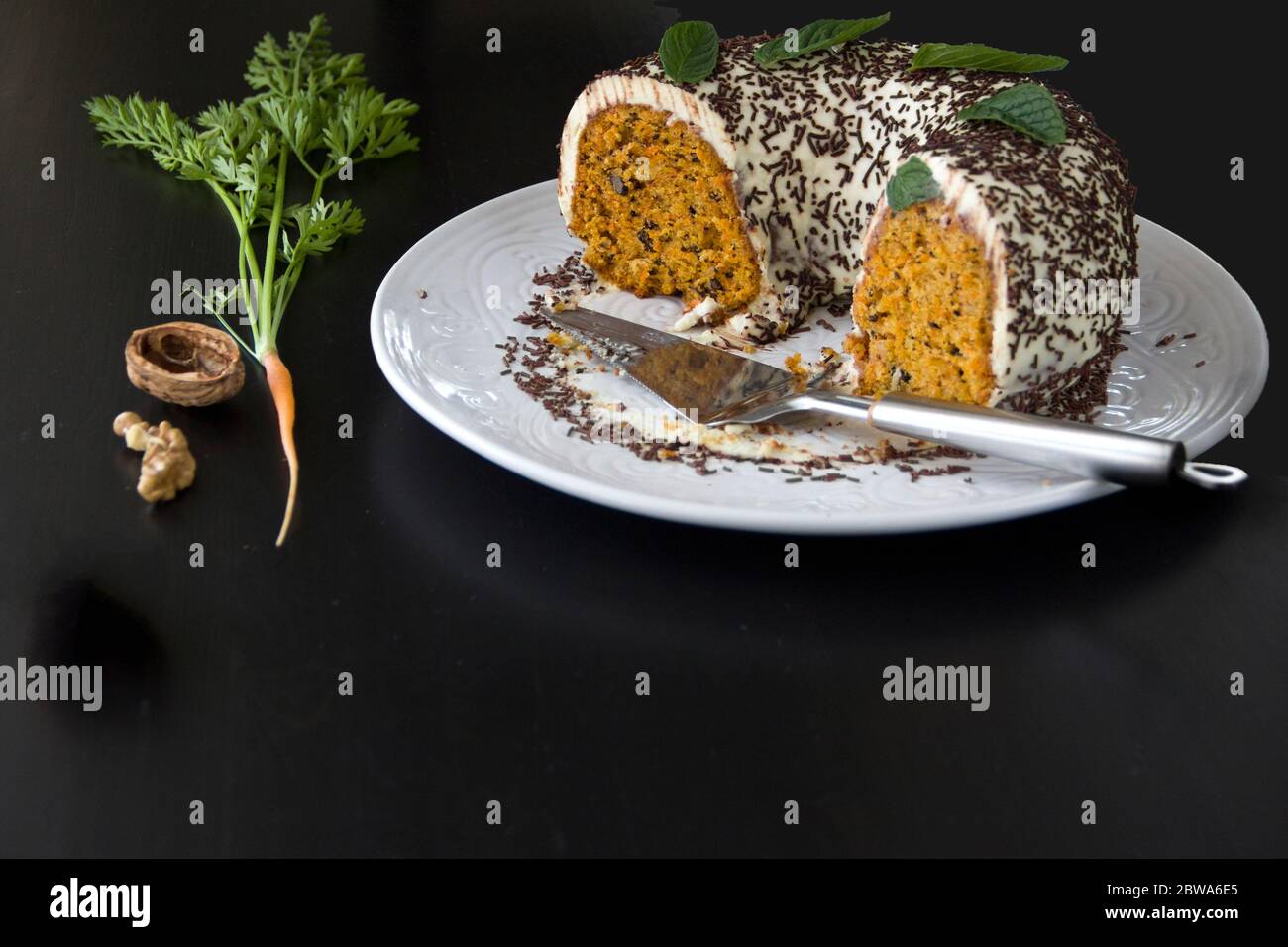 Hausgemachter Karottenkuchen auf einem großen weißen Gericht auf dunklem Hintergrund. Selektiver Fokus, Kopierbereich Stockfoto