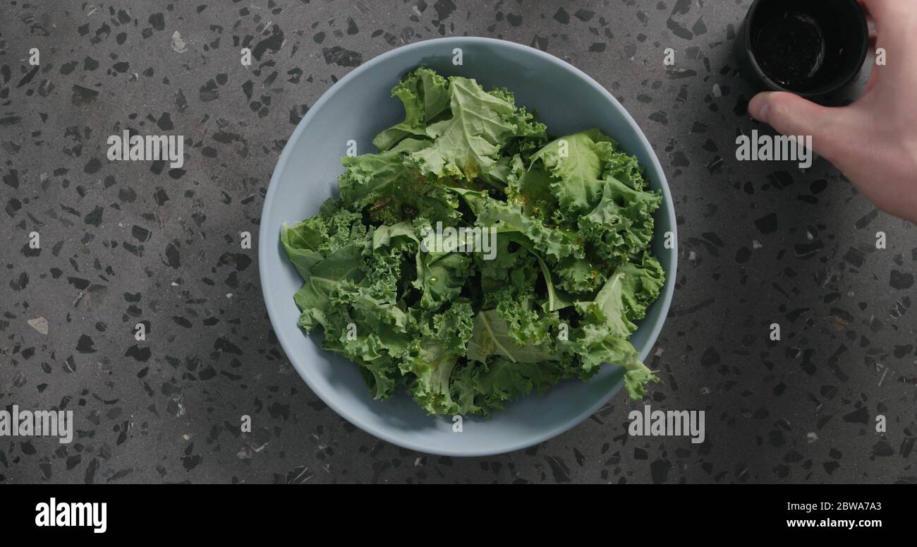 Draufsicht massierte Grünkohl-Blätter in blauer Keramikschale auf Konkreter Hintergrund Stockfoto