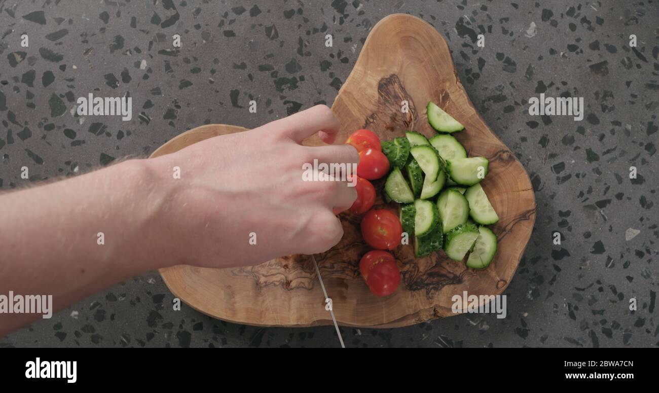 Draufsicht Mann Hände schneiden Kirschtomaten auf Beton Arbeitsplatte Stockfoto