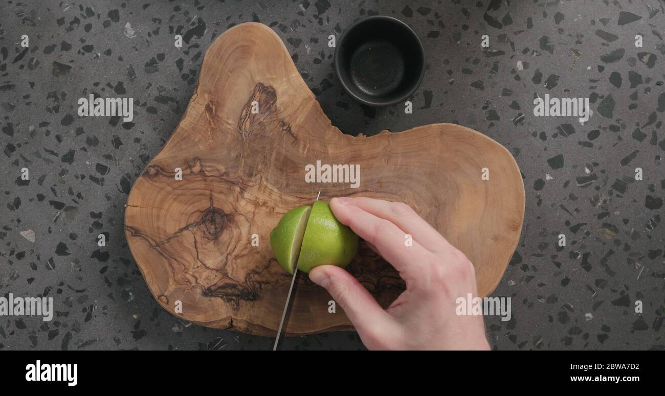 Draufsicht man Hände schneiden Kalk auf Beton Arbeitsplatte Stockfoto