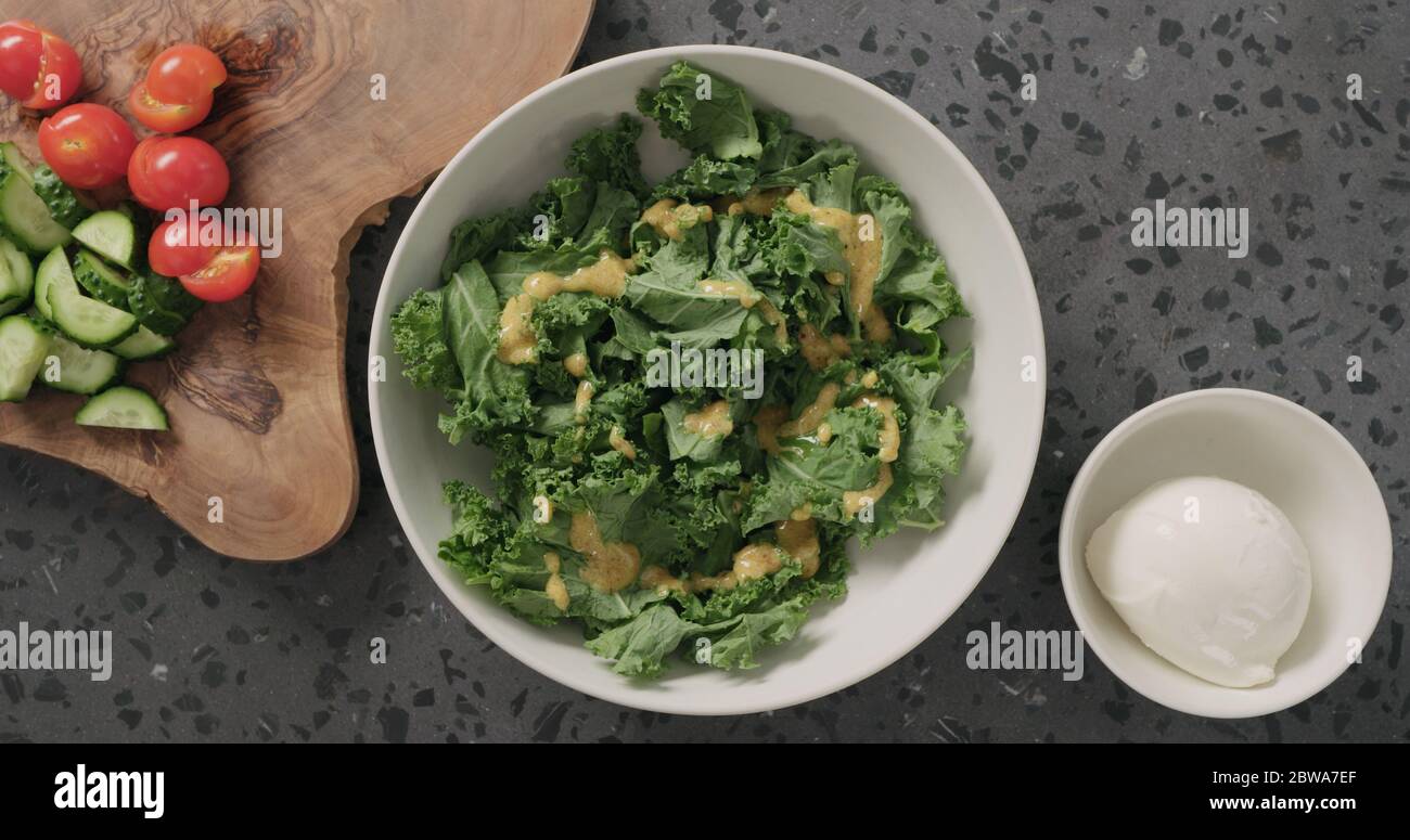 Draufsicht massierte Grünkohl-Blätter in weißer Keramikschale auf Konkreter Hintergrund Stockfoto