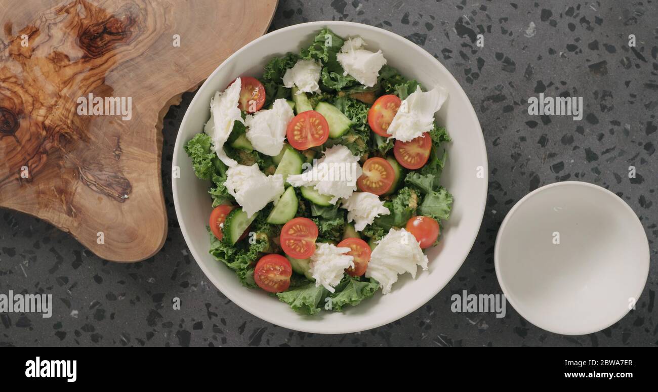 Draufsicht Mozzarella über Grünkohlensauce und Tomaten in weiß zugeben Keramikschale auf Beton Hintergrund Stockfoto