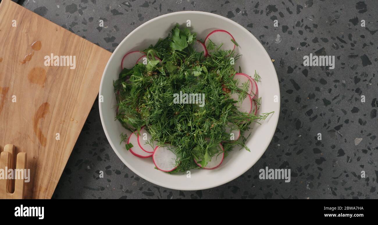 Draufsicht Salat aus Rettich, Gurken, Grünkohl und Kräutern mit Dressing mischen Stockfoto