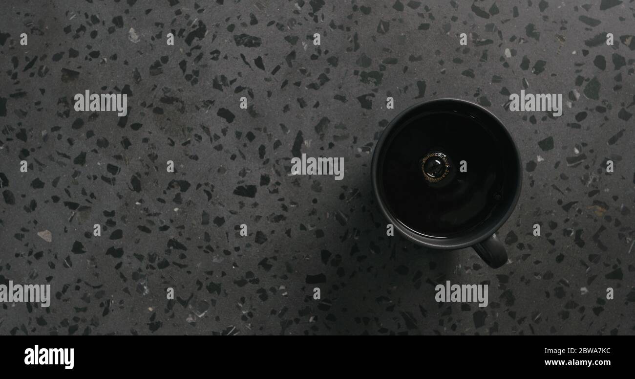 Schwarzer Kaffee in schwarzer Tasse auf Beton Hintergrund Draufsicht Stockfoto
