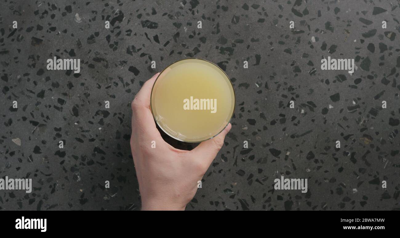 Man Hand nimmt Limonade in Glas auf Beton Hintergrund Stockfoto
