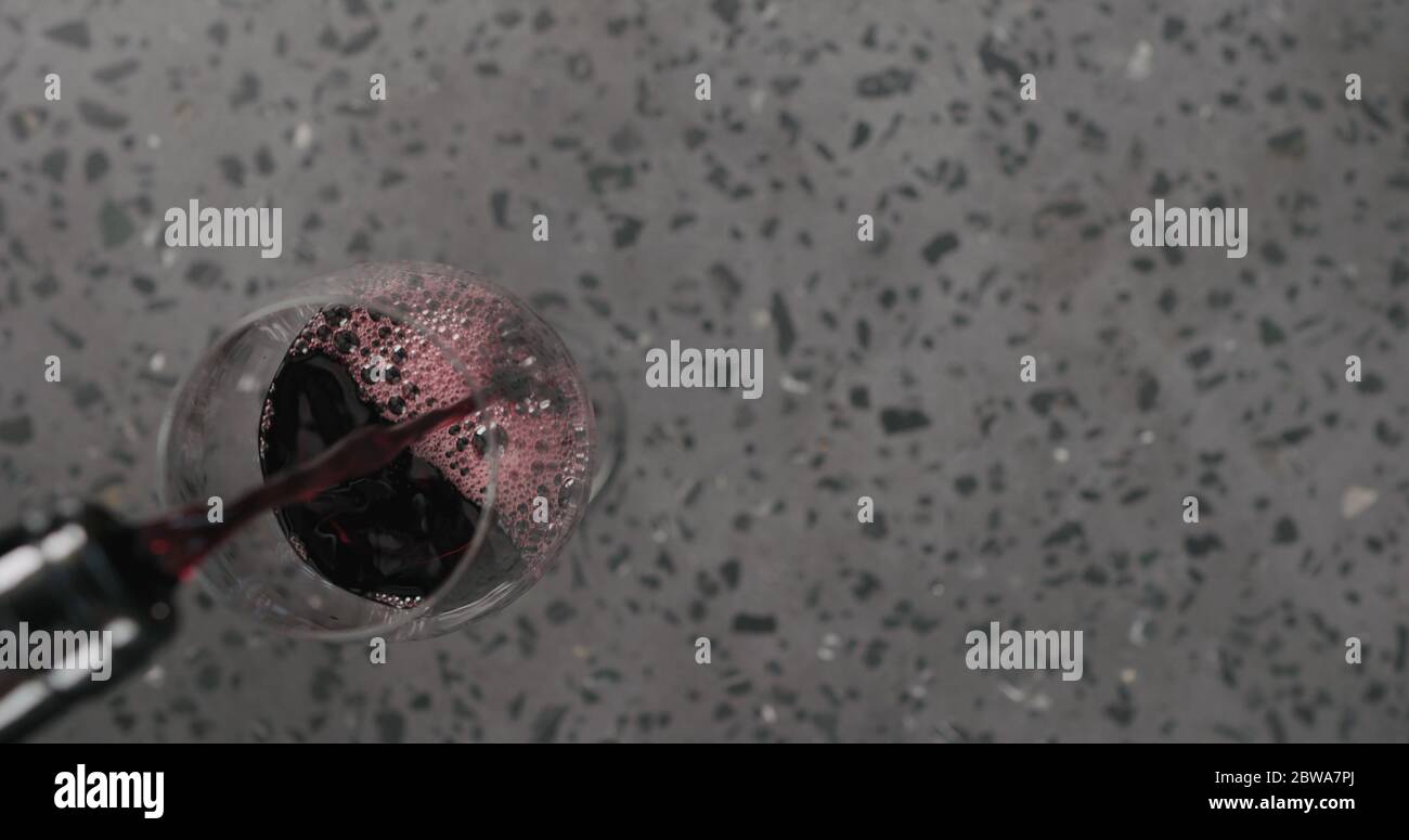 Draufsicht gießen Rotwein in Weinglas auf Beton Hintergrund Mit Kopierbereich Stockfoto