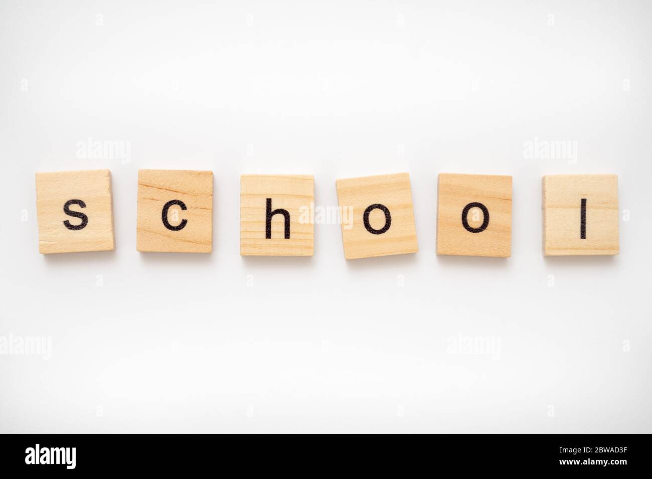 Hölzerne Buchstabenkacheln, die das Wort SCHULE buchstabieren Stockfoto