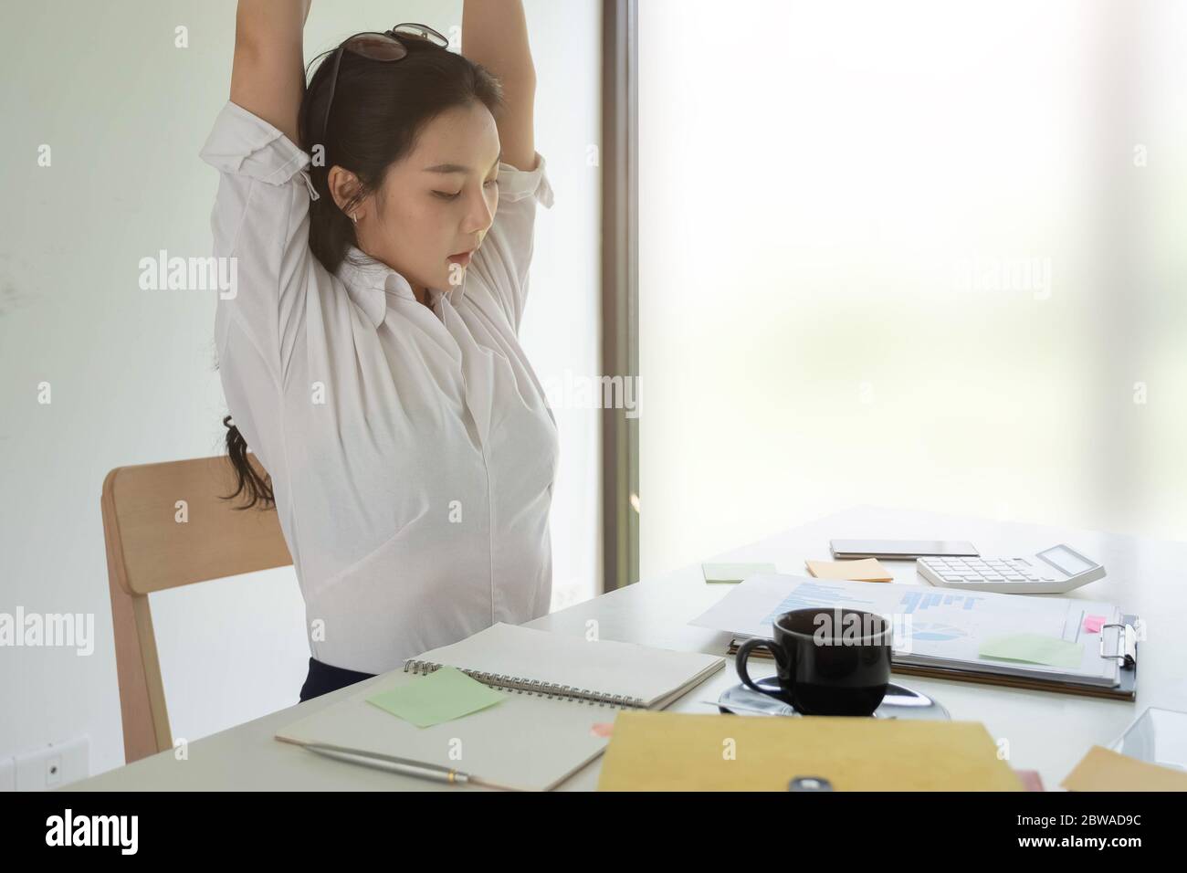 Geschäftsfrau entspannt sich in bequemen Büro Hände hinter dem Kopf, glückliche Frau im Büro Ruhe zufrieden nach der Arbeit Stockfoto