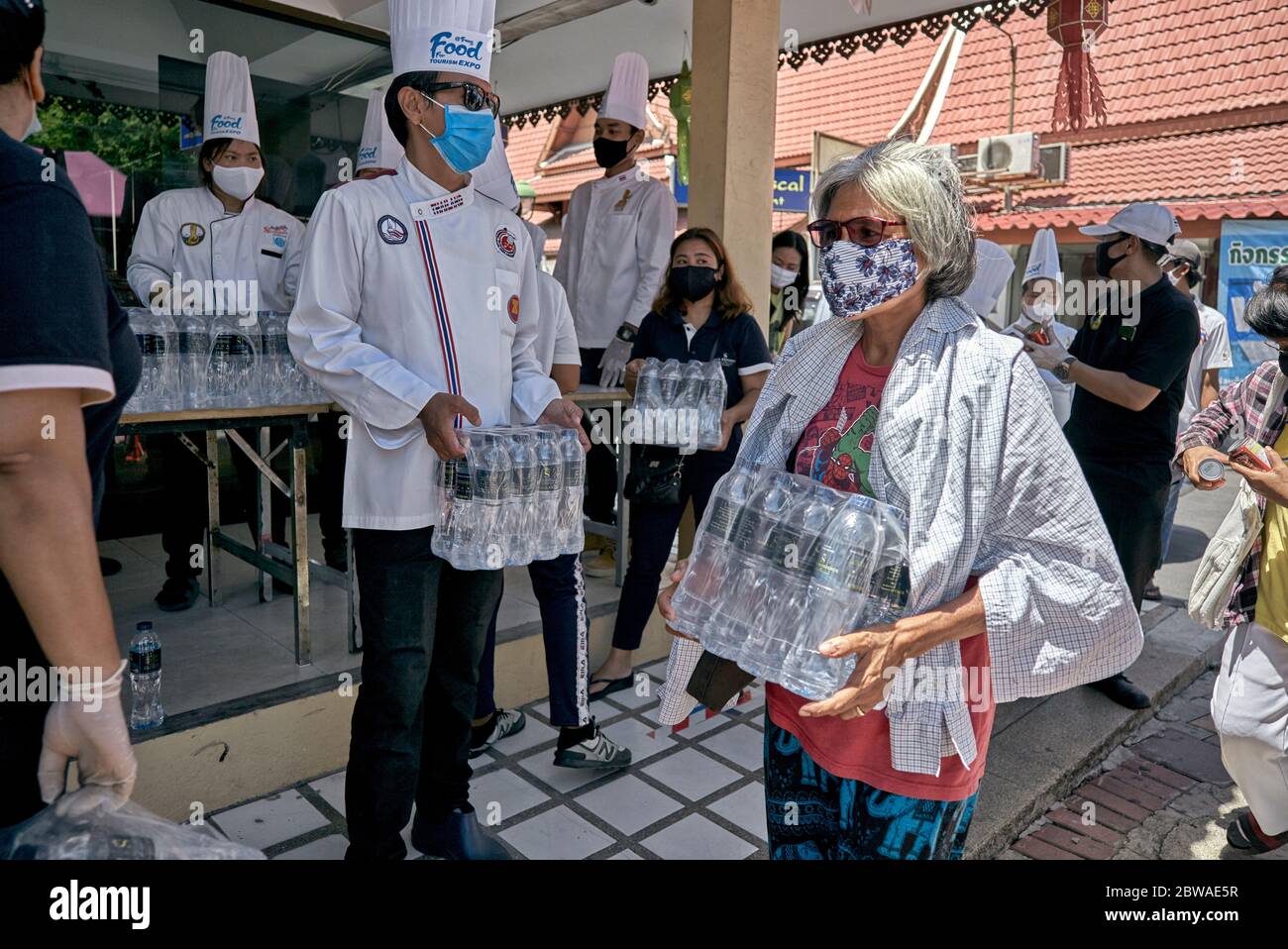 Covid-19 Essen. Kostenlose Lebensmittelzureichung an Menschen in Not aufgrund von Einkommensverlusten durch Coronavirus. Menschen geben Essen mit Masken. Thailand Asien Stockfoto