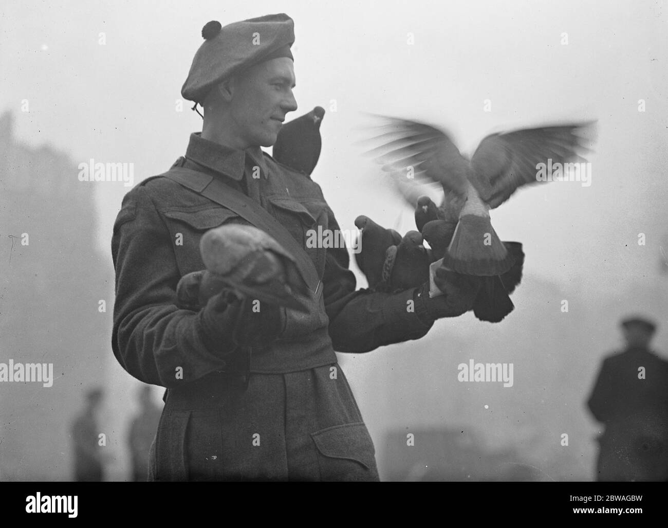 Ein Mitglied der kanadischen Streitkräfte füttert die Tauben auf dem Trafalgar Square. Januar 1940 Stockfoto