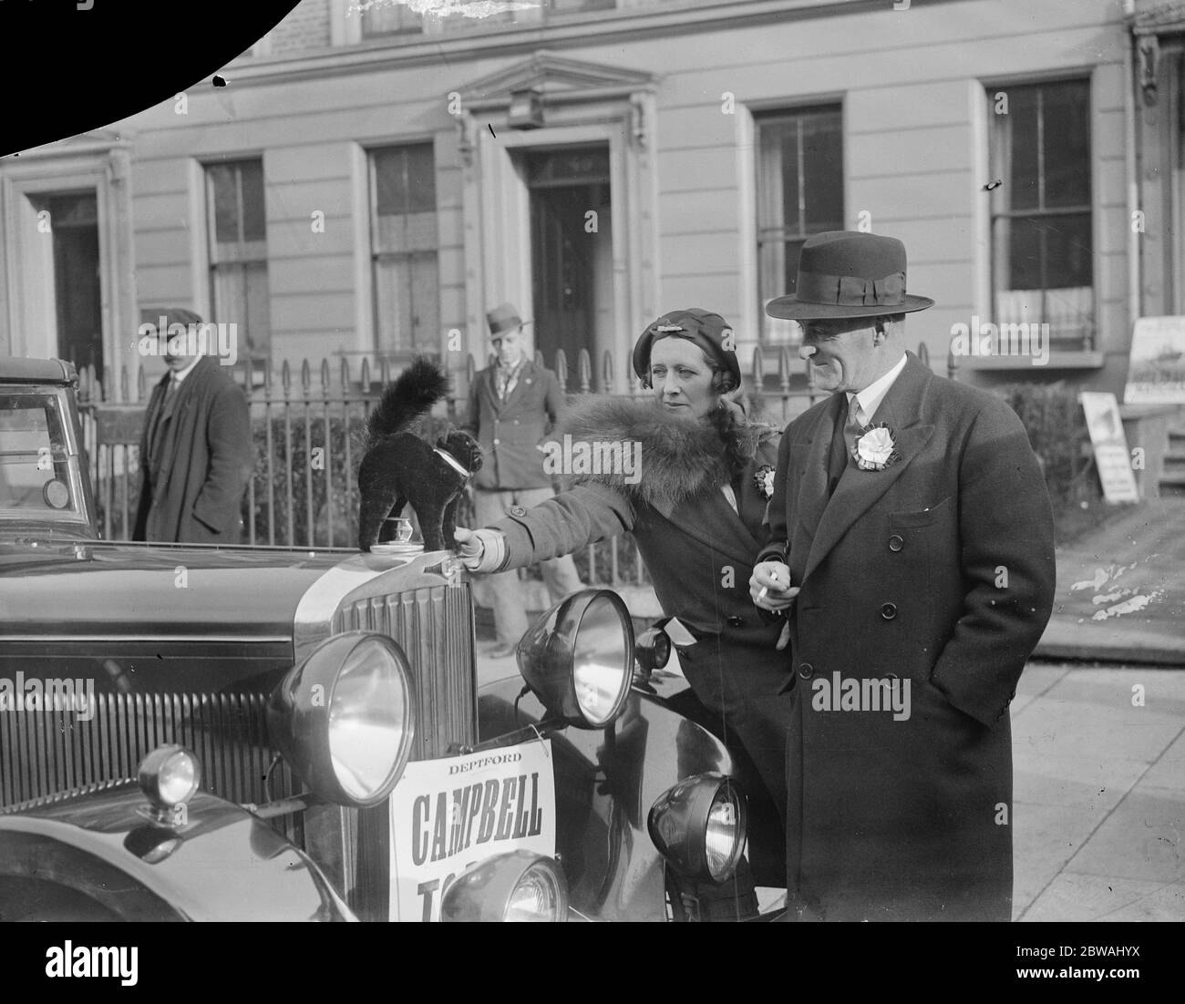 Die Parlamentswahlen Sir Malcolm und Lady Campbell fixieren während ihrer Kampagne in New Cross am 14. November 1935 ein schwarzes Maskottchen auf ihrem Auto Stockfoto