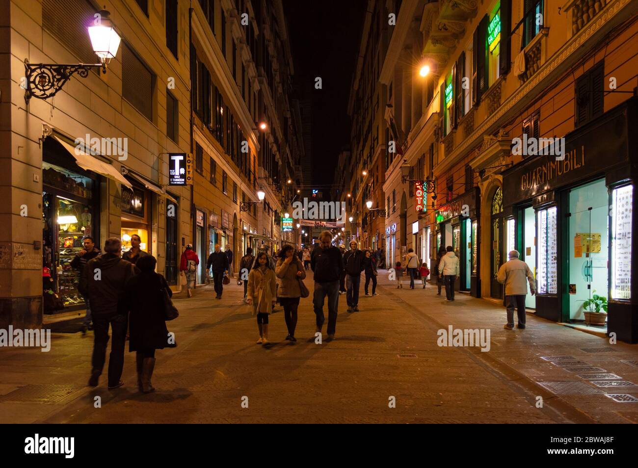 Eine Gasse in Genua mit vielen Fußgängern. Nachtleben in Genua. Stockfoto
