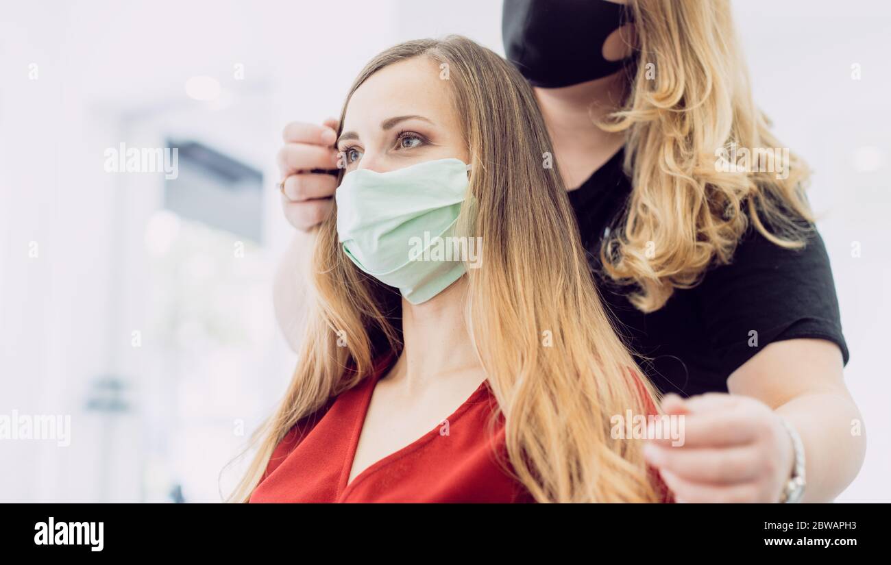 Frau mit frischem Haar Styling in Friseurladen mit Gesichtsmaske Stockfoto