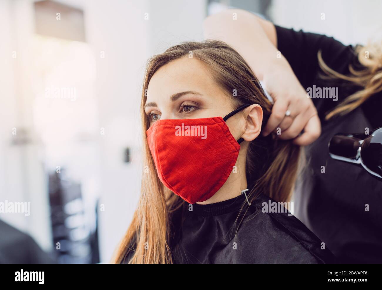Frau trägt rote Gesichtsmaske immer frisches Styling bei einem Friseur Stockfoto