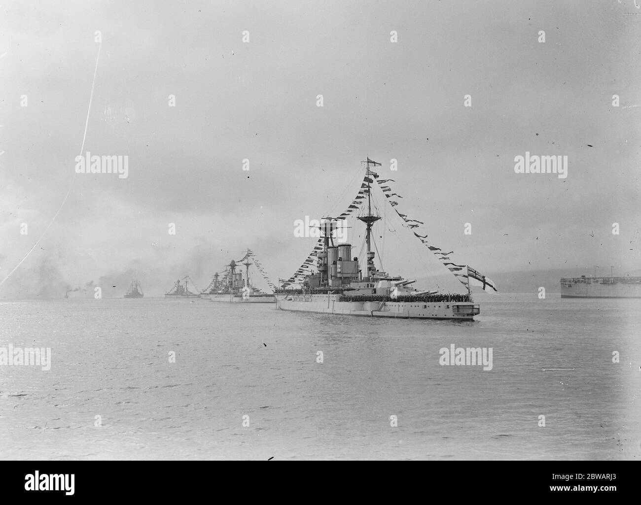Königliche Reise nach Schottland EIN Foto von der Royal Yacht "Victoria und Albert", wie es die Linie der Schlachtschiffe in Rothesay, Bute vorbei an der "HMS Warspite" im Vordergrund - alle Männer an Deck in Gruß 12 Juli 1920 Stockfoto