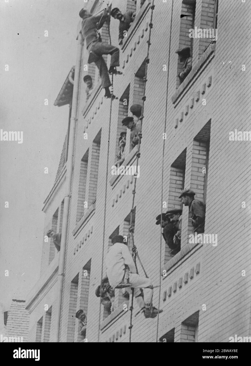 Affen wie Klettern mit Affen Apparat. Das neue Gerät und das alte Outfit, das von einem anderen Arbeiter getragen wird. 13 Mai 1921 Stockfoto