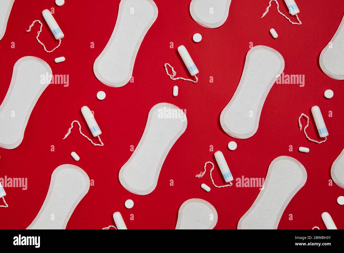 Weiße Damenbinden und Tampons aus reiner Baumwolle auf rotem Hintergrund isoliert. Feminine Hygieneprodukte Stockfoto