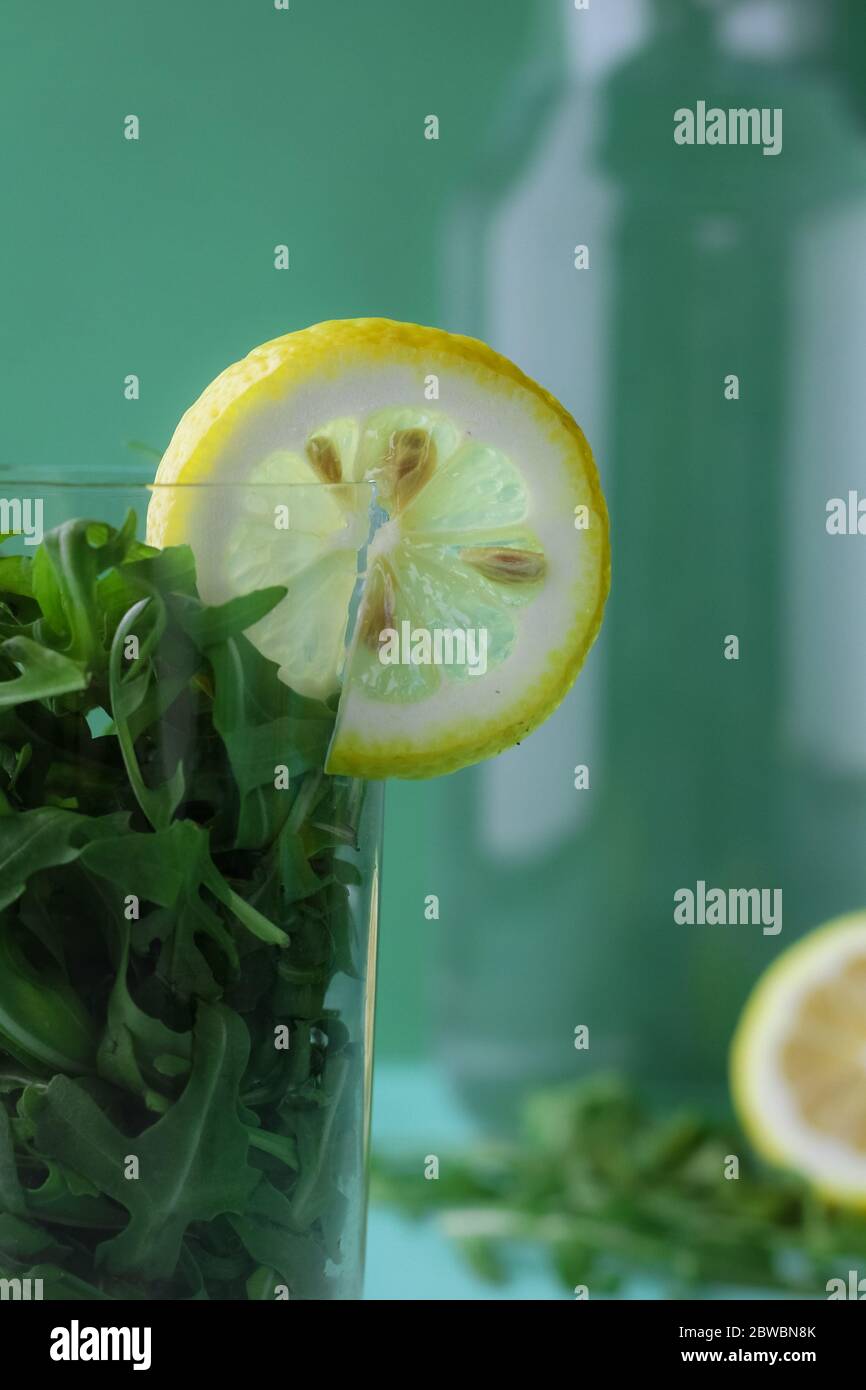 Grüner Gemüse-Smoothie, Cocktail aus Grüns und Zitronenscheibe vor trendigem tiefgrünem Hintergrund Stockfoto