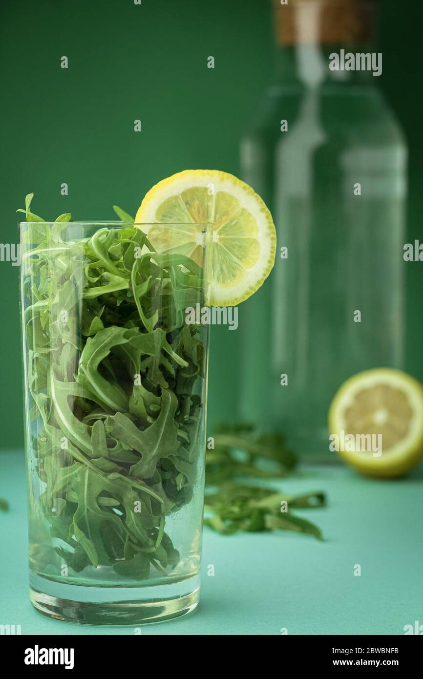 Grüner Gemüse-Smoothie, Cocktail aus Blättern und Zitronenscheibe auf trendigen tiefgrünen Hintergrund Stockfoto