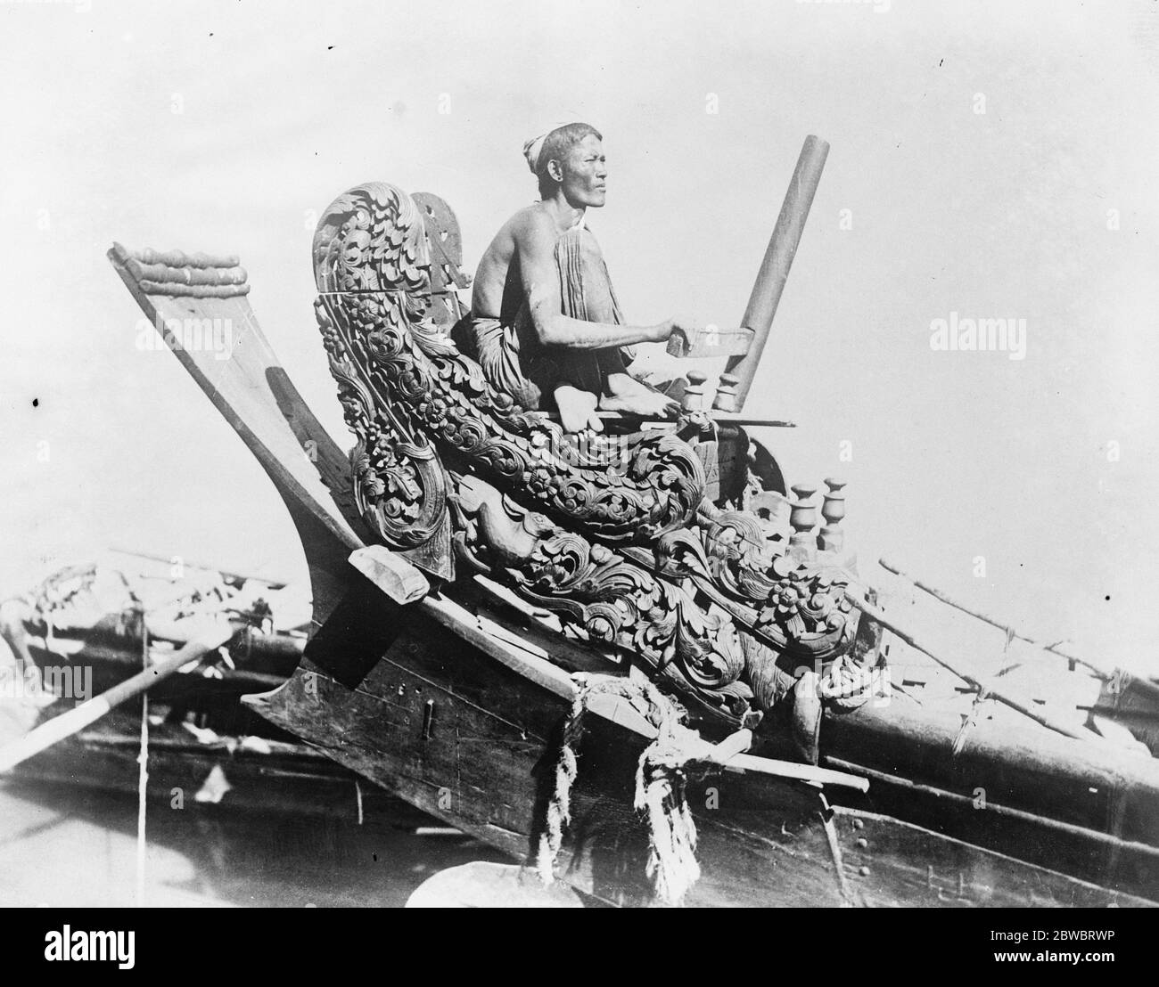 Die cox einer Königin basteln ein Interessantes Bild aus Burma, das den Steuermann eines Flussbootes in seinem wunderschön geschnitzten Sitz zeigt 27. Januar 1926 Stockfoto