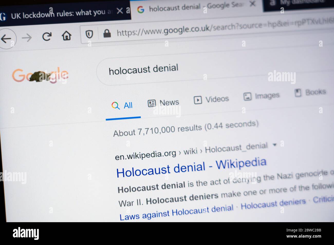 Ein Computerbildschirm, der die Wörter 'Holocaust-Leugnung' als Google Search Enginesuchbegriff zeigt. Konzept - Verschwörungstheorie, Verschwörungstheorien Stockfoto