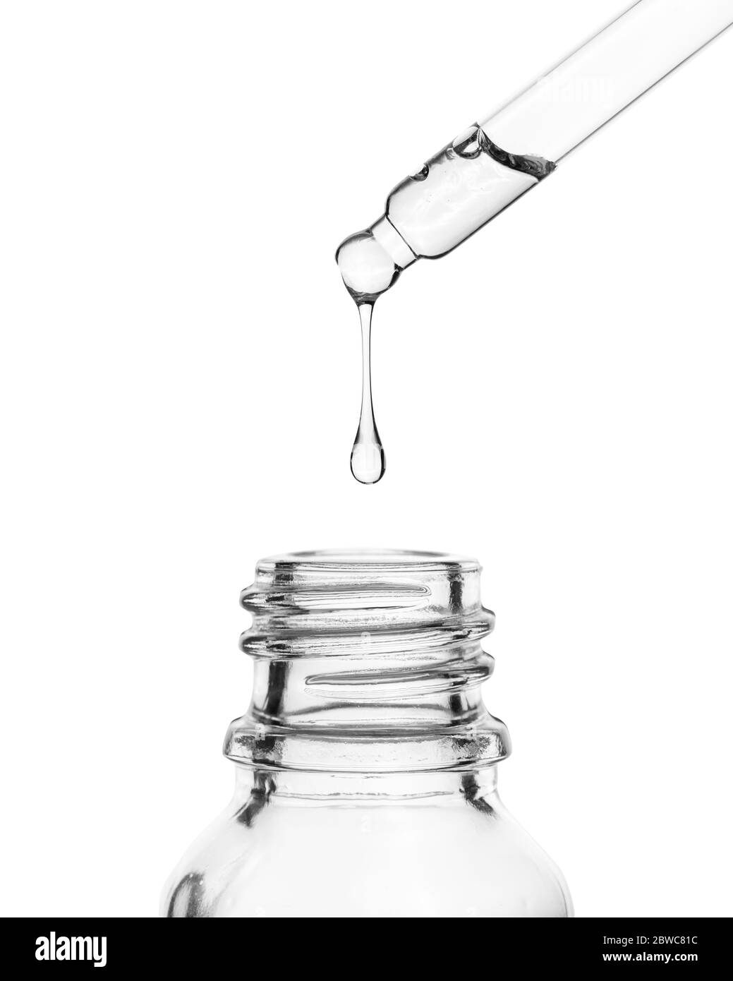 Ein Tropfen fällt in eine Glasflasche. Kosmetisches Öl tropft aus einer Pipette auf weißem Hintergrund. Stockfoto