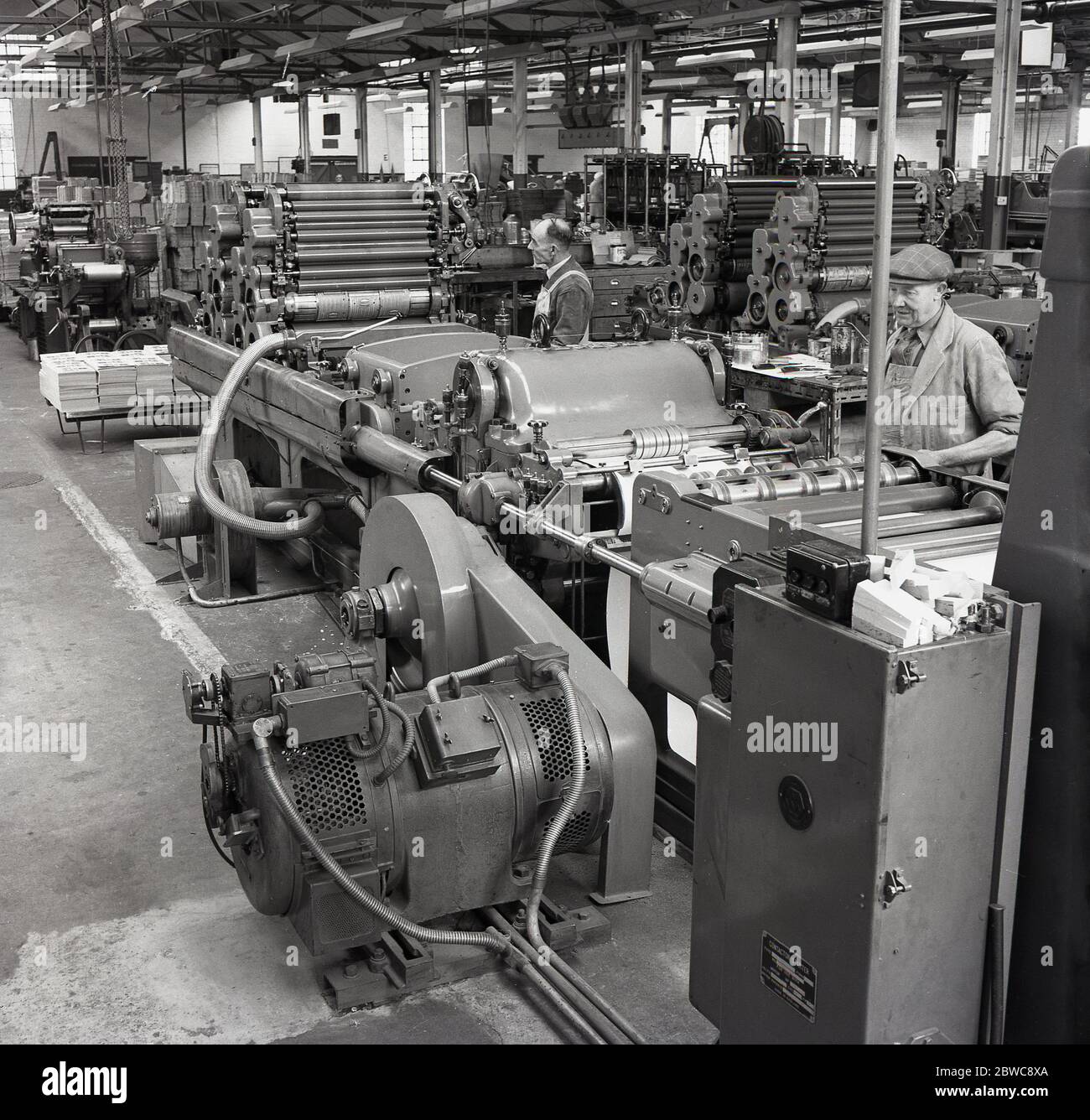 1950er Jahre, historische, Innenansicht der Druckmaschinen mit männlichen Arbeitern in Overalls Betrieb der Maschinen, um Verpackungen in einer Fabrik für die Batterieherstellung, england, Großbritannien. Stockfoto