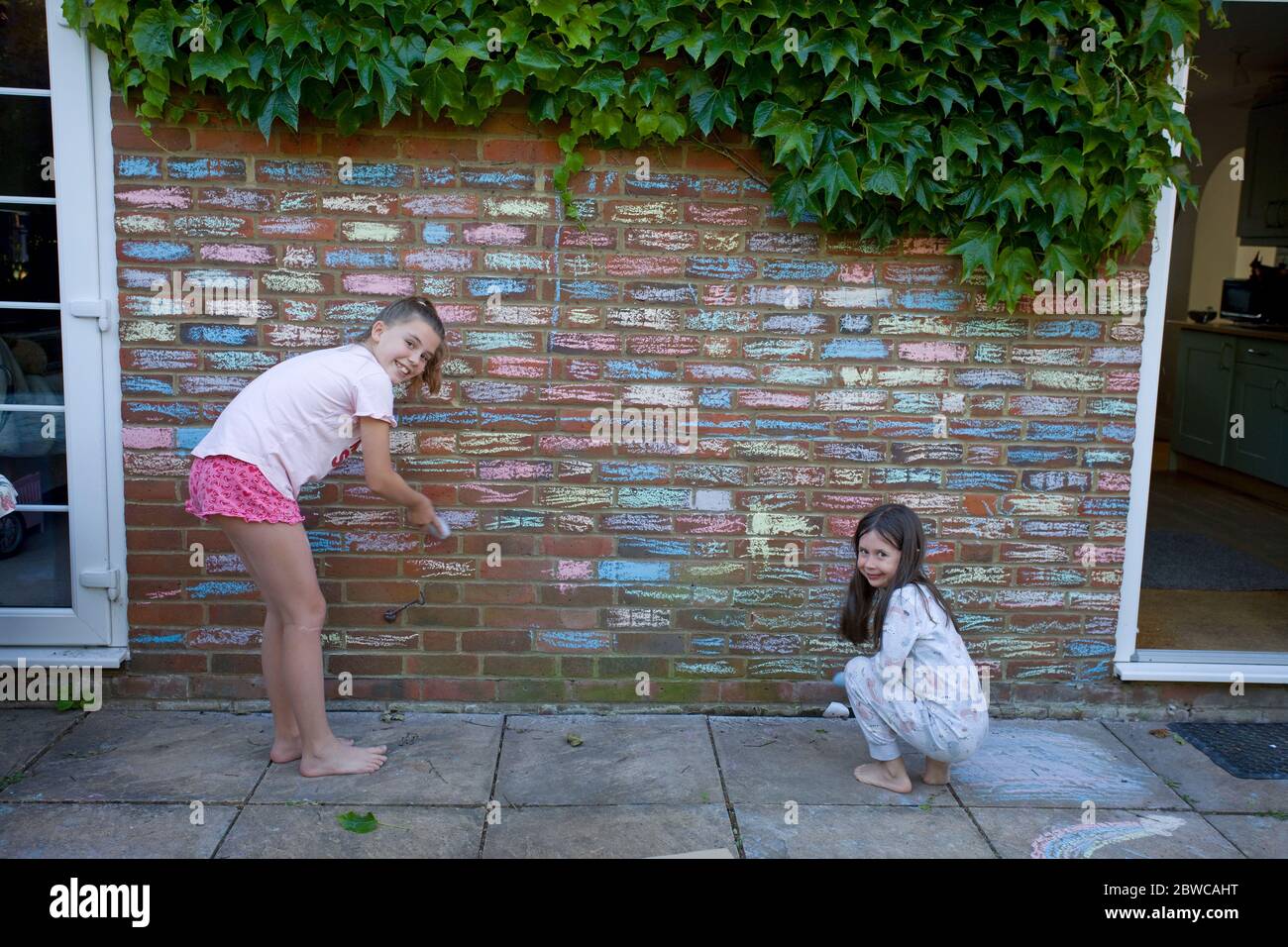 Junge Mädchen Färbung in Haus Ziegel mit Kreidepastelle, UK Stockfoto