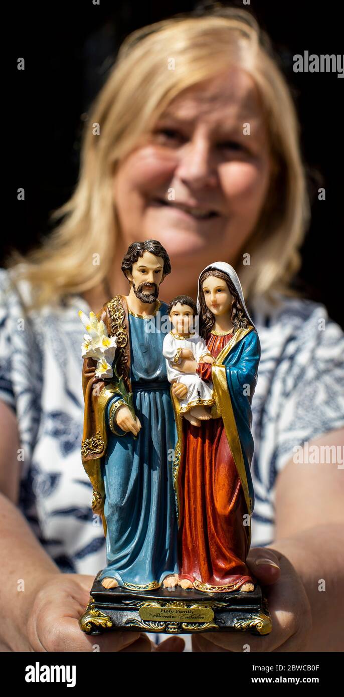 Jackqui Magee hält eine Statue der Heiligen Familie, die von P. Tim Bartlett von der St. Mary?? S Kirche in Belfast gesegnet wurde. Die Gemeindemitglieder baten die Kirche, die Gemeinde zu besuchen, um während der Sperrung das Heilige Wasser zu liefern. Stockfoto