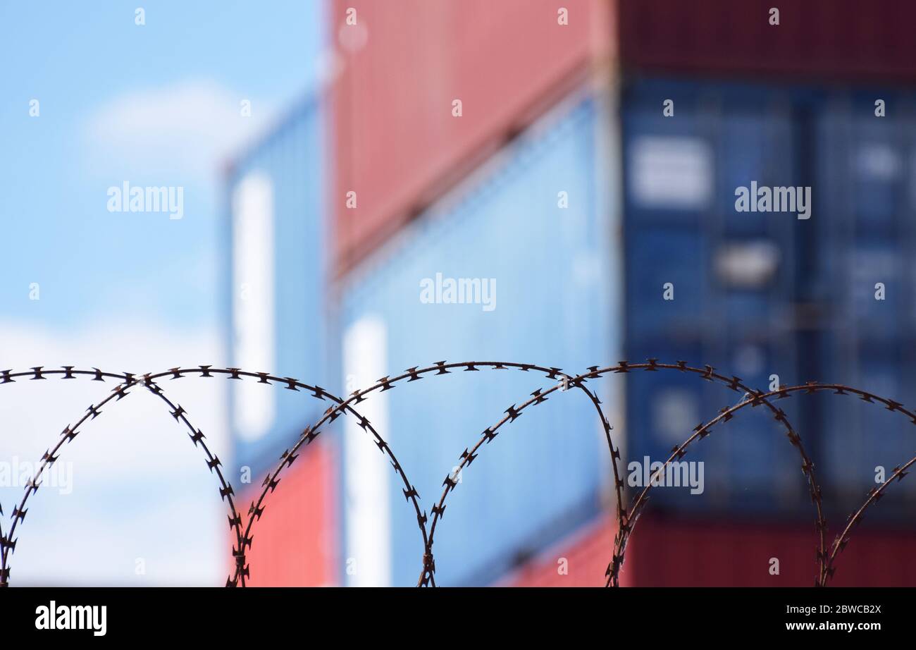 Hinter Stacheldraht stapelte Frachtcontainer an einem belebten europäischen Seehafen Stockfoto