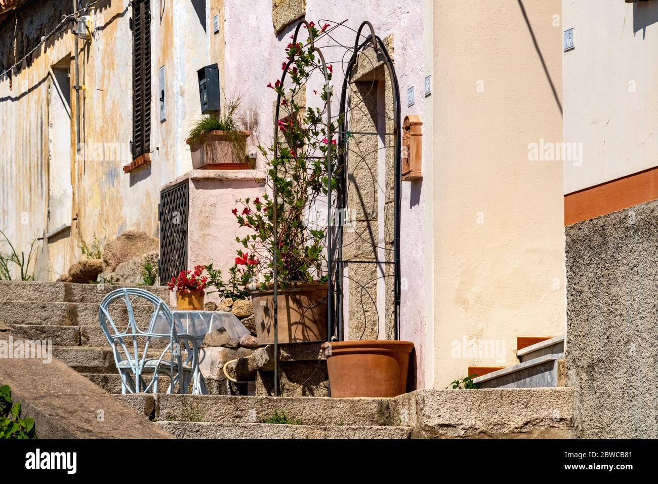 Home Komfort: Tisch und Stuhl mit Pflanzen auf Treppen außerhalb ein traditionelles Reihenhaus im Dorf San Pantaleo, Gallura, Sardinien, Italien. Stockfoto