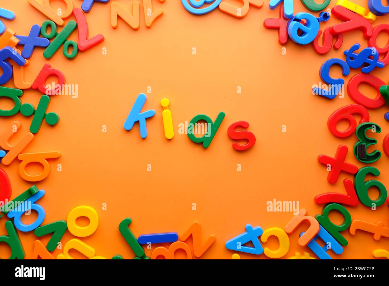 Kinder Wörter in bunten Kunststoff Buchstaben auf orangefarbenem Hintergrund. Stockfoto
