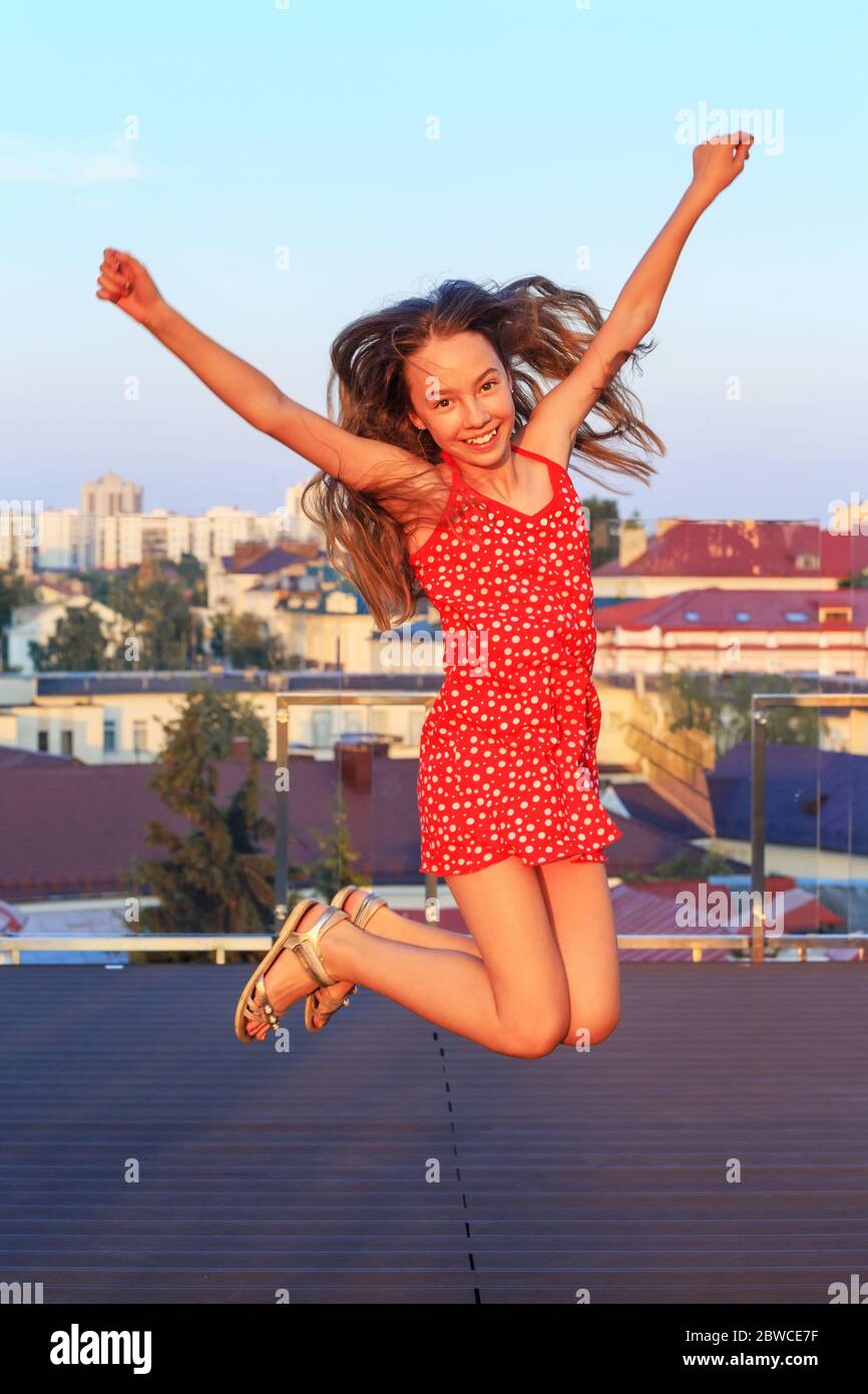 Porträt eines niedlichen Teenager-Mädchen lächelnd und springen im Freien am Sommerabend Stockfoto