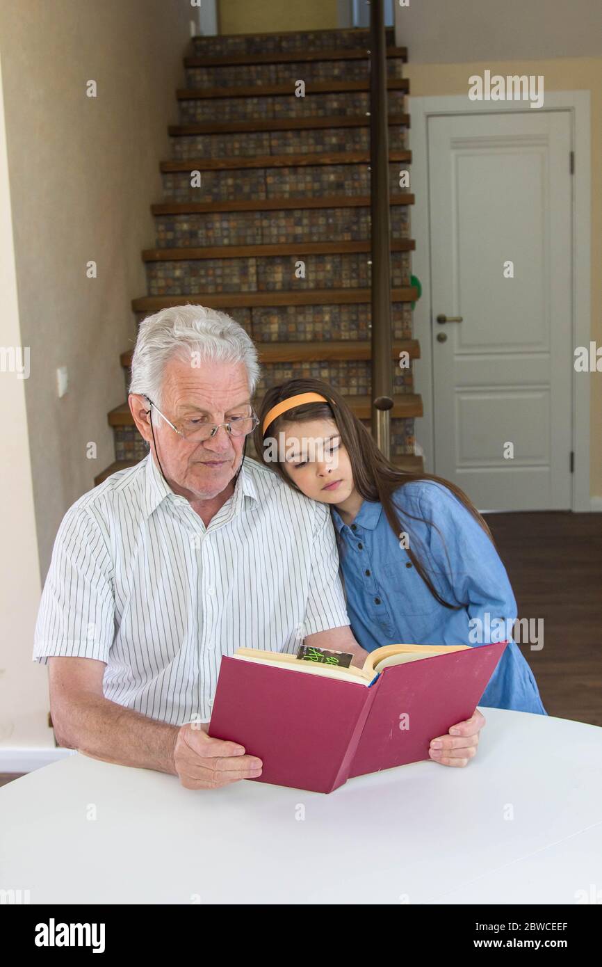 Großvater und Enkelin lasen ein Buch im Haus und haben eine gute Zeit zusammen Stockfoto