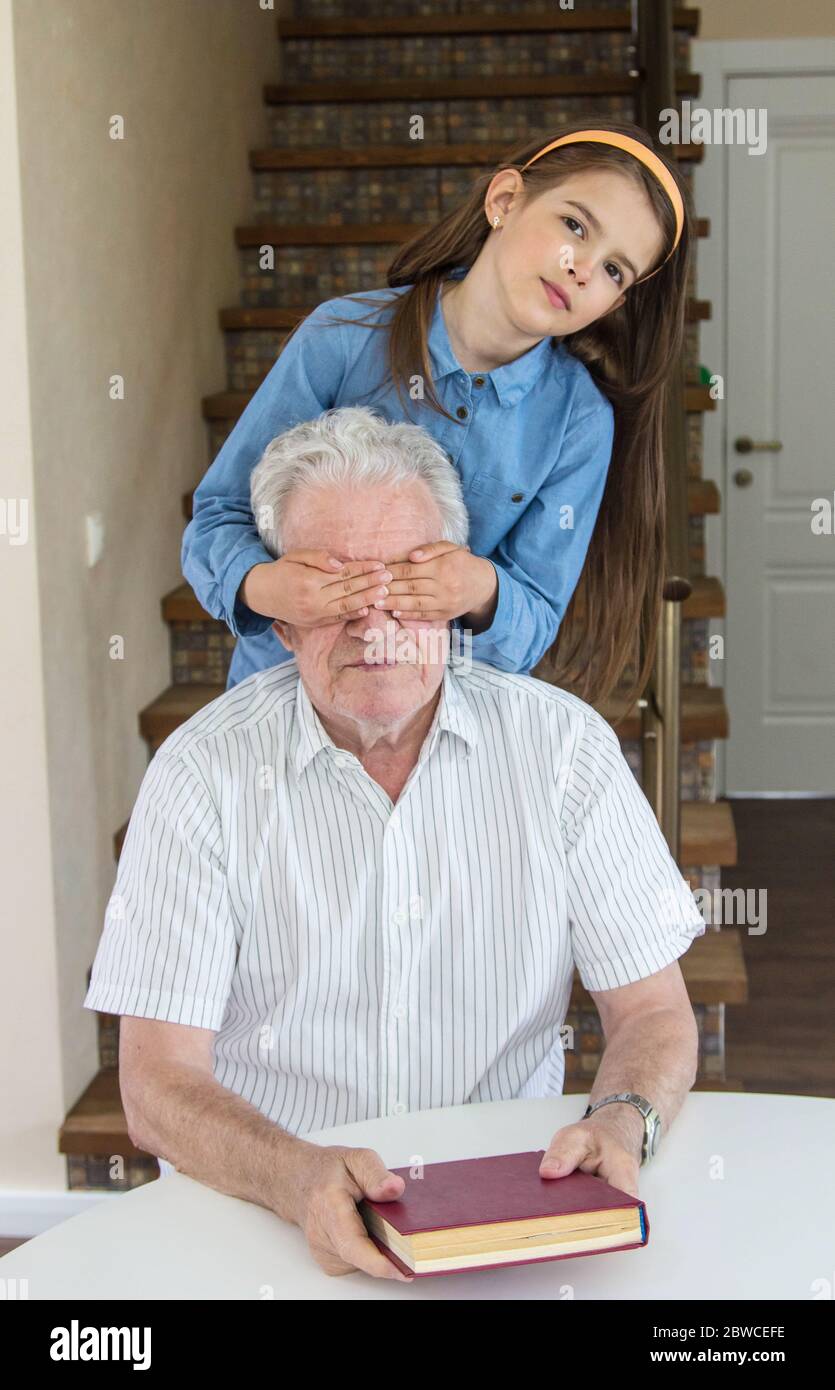 Großvater und Enkelin lasen ein Buch im Haus und haben eine gute Zeit zusammen Stockfoto
