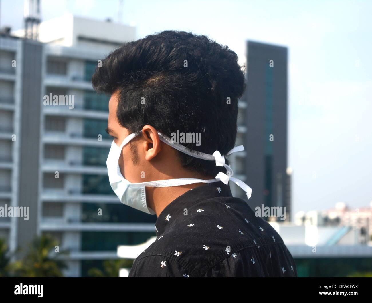 Seitenansicht des jungen Mannes trägt chirurgische Gesichtsmaske auf einem Hintergrund der Corporate Company.Corona Virus, Quarantäne. Stockfoto