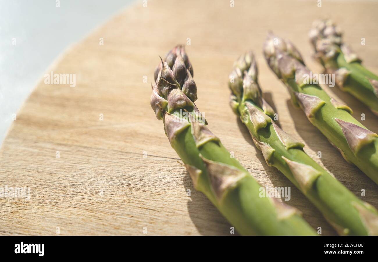 Detail von frischen grünen Asparagus Köpfe auf einer hölzernen Küche Boad mit hellem Licht Stockfoto