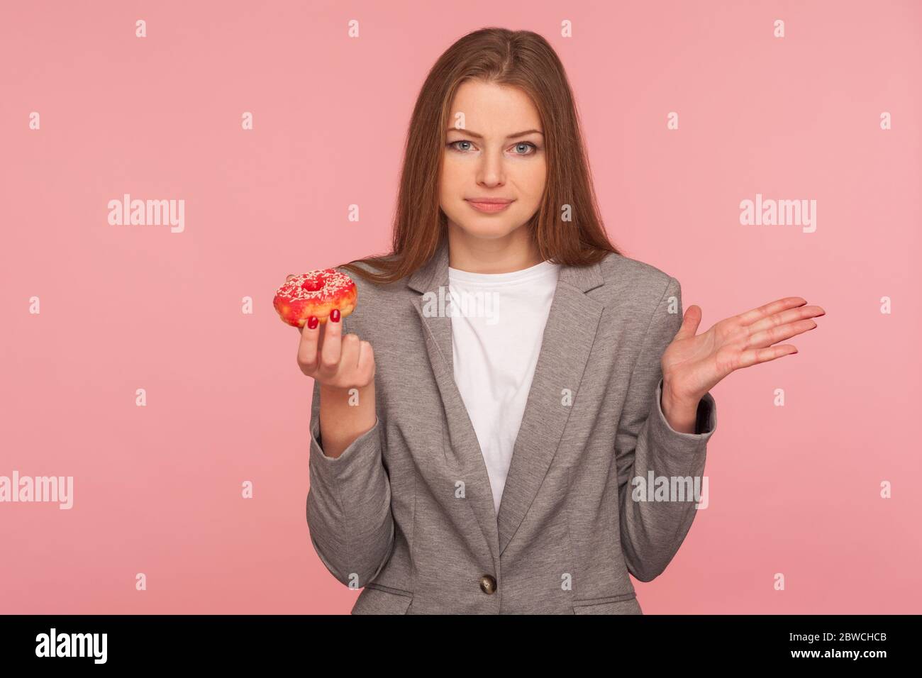 Porträt der verwirrten Frau, Büroangestellter im Business-Anzug, der süßen Donut hält und Gesturing Verwirrung, Zweifel, Donut-Gebäck zu essen, ungesund Stockfoto