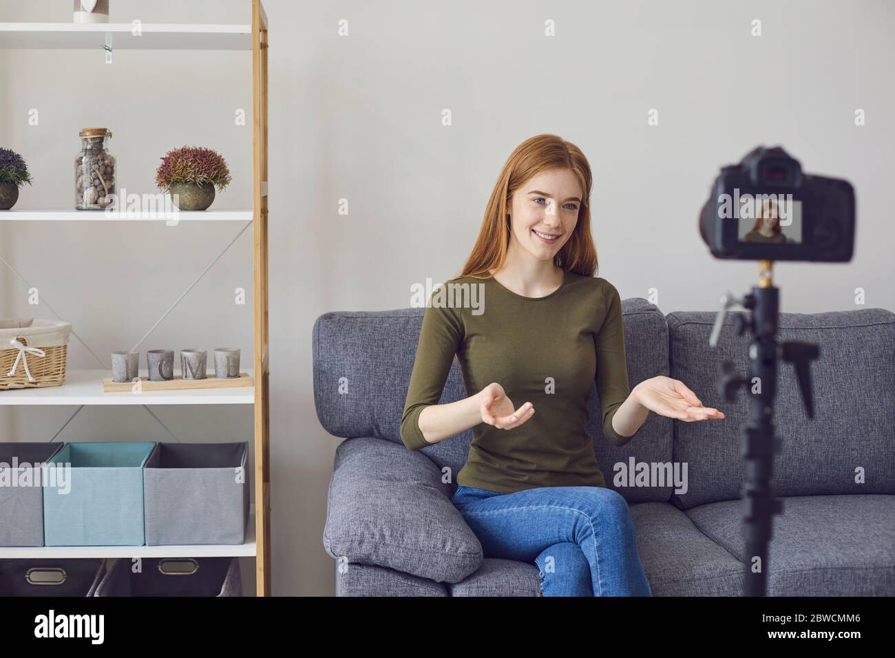 Blogger Vlogger Mädchen spricht mit der Kamera, während auf einem Sofa in einem Raum zu Hause sitzen. Stockfoto