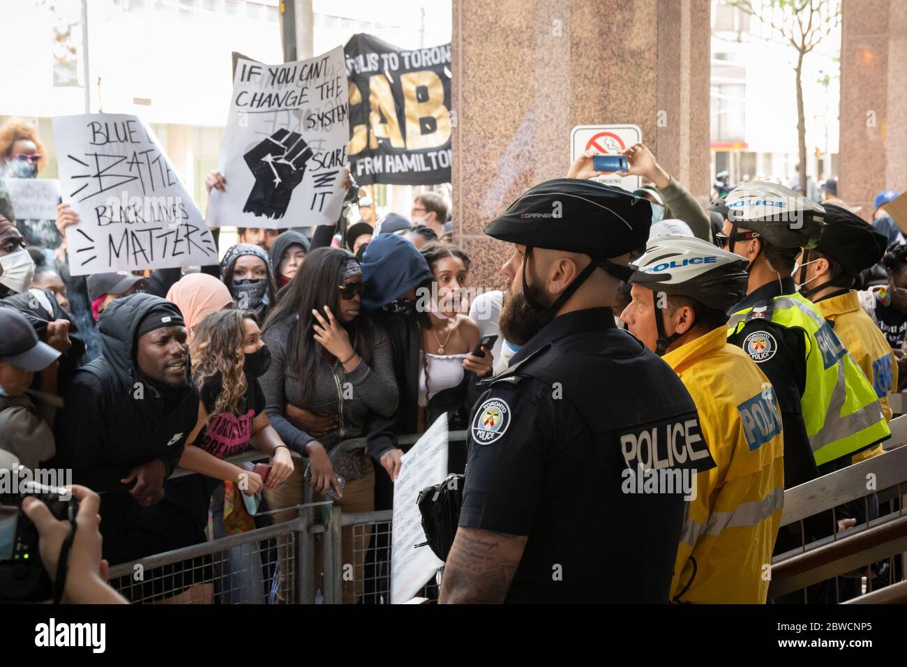 Demonstranten schreien, während Polizisten ruhig bei einem "Not Another Black Life"-Protest nach dem Tod von Regis Korchinski-Paquet in Toronto stehen. Stockfoto