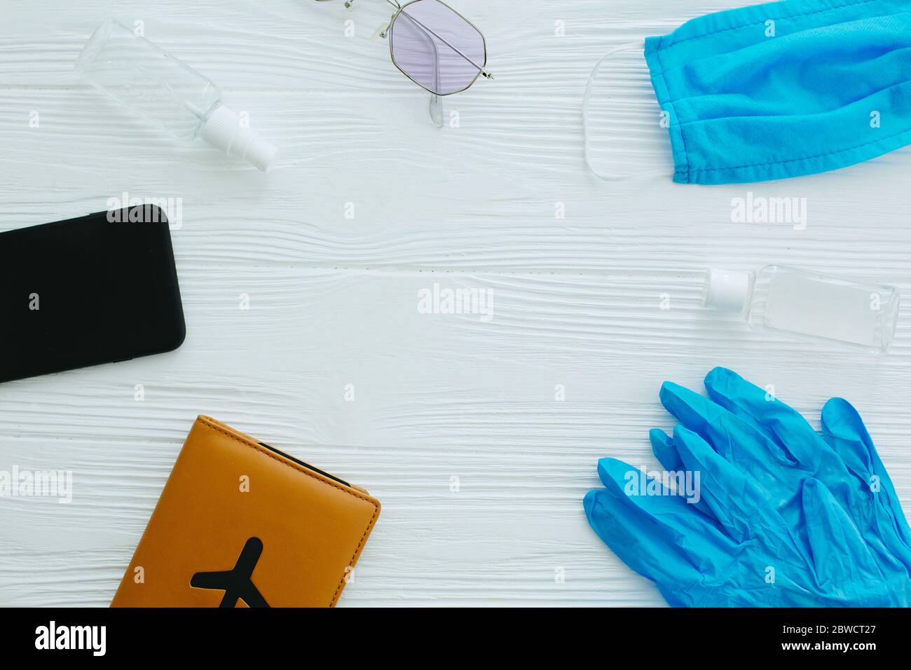 Blaue Gesichtsmaske, Handschuhe, Antiseptikum und Desinfektionsmittel, Reisepass, Sonnenbrille und Telefon auf weißem Hintergrund, Kopierraum. Sichere Reise im Sommer 2020. Coro Stockfoto