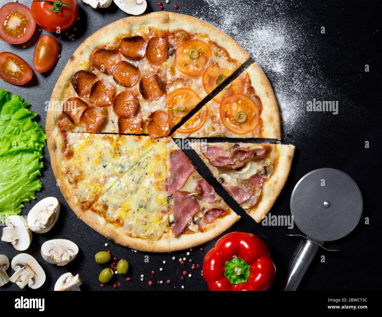 Italienische Pizza und Zutaten und Gewürze zum Kochen von Pilzen, Tomaten, Pfeffer, Salz, Kräutern und lebendig auf schwarzem Beton Hintergrund.Draufsicht auf piz Stockfoto