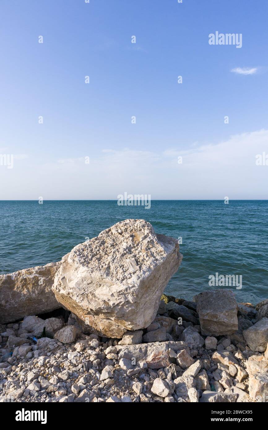Großes Kopfsteinpflaster liegt an einem felsigen Strand. Mit klarem, blauen Himmel Hintergrund. Stockfoto
