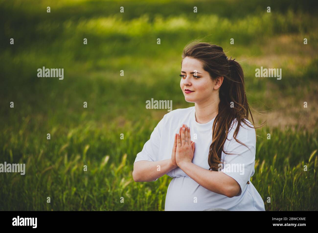 Gesunde schwangere Frau macht Yoga in der Natur im Freien. Stockfoto