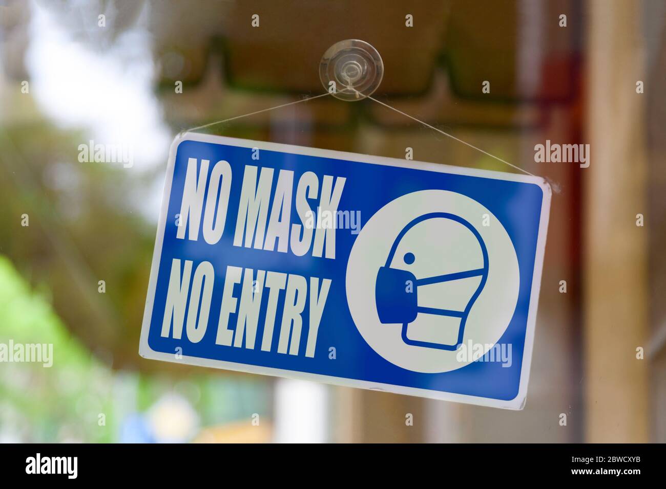Nahaufnahme auf einem blauen offenen Schild im Fenster eines Shops mit der Meldung „Keine Maske, kein Eintrag“. Stockfoto