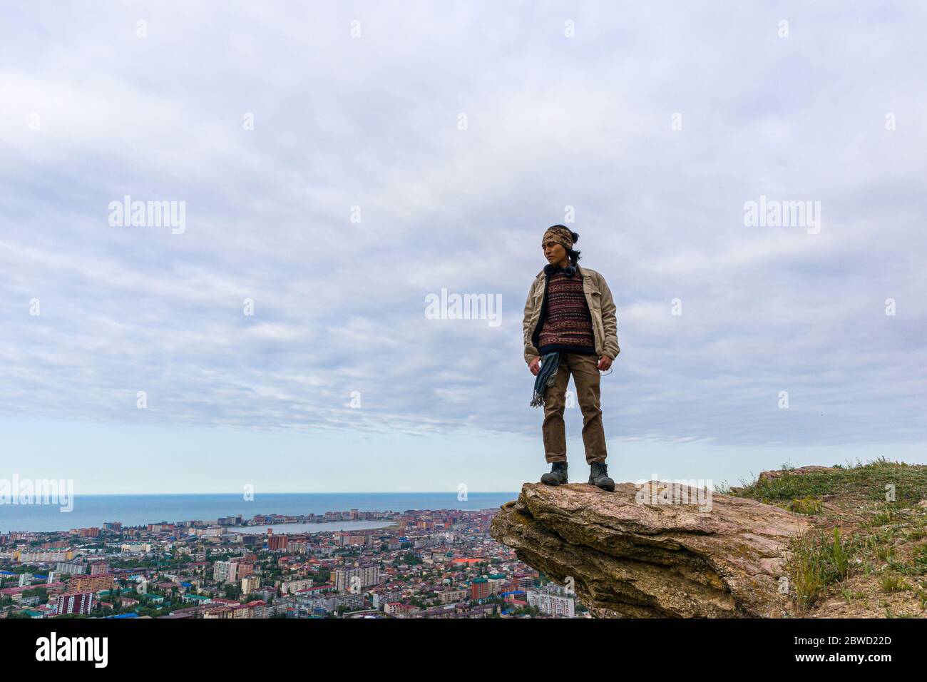Machatschkala, Dagestan. Russland - 30. Mai 2020: Ein Mann steht auf einem Stein am Hang des Berges über der Stadt, nahe dem Kaspischen Meer. Stockfoto