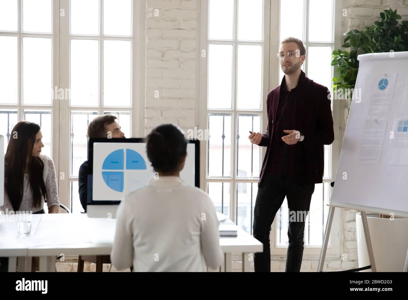 Männlicher Redner, der konzentrierten Kollegen Marketingstrategien auf dem Flipchart vorstellt. Stockfoto