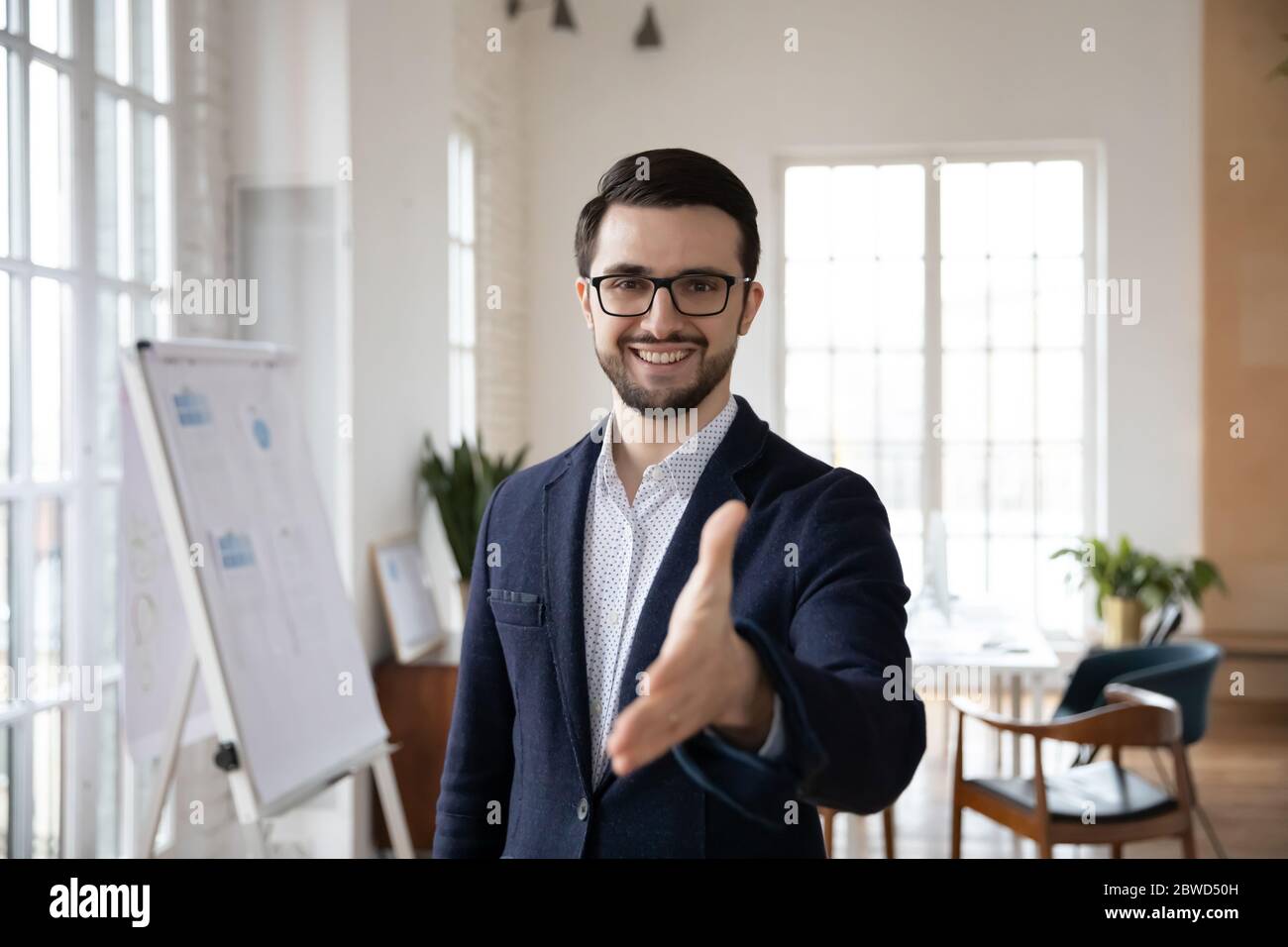 Ein freundlicher, lächelnder und vertrauensvoller Manager im Anzug, der sich die Hand ausstreut. Stockfoto